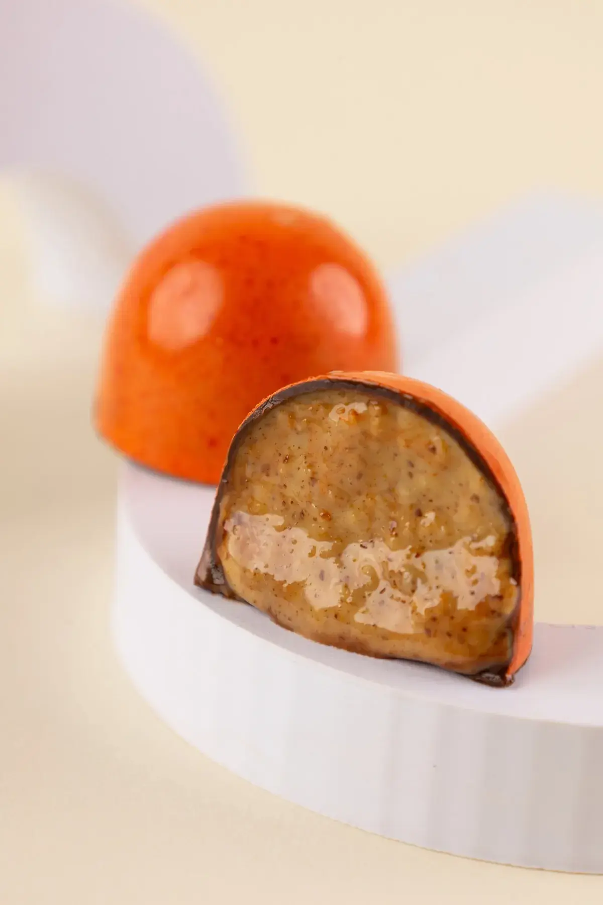 Bombom laranja cortado ao meio, com recheio de caramelo e castanhas